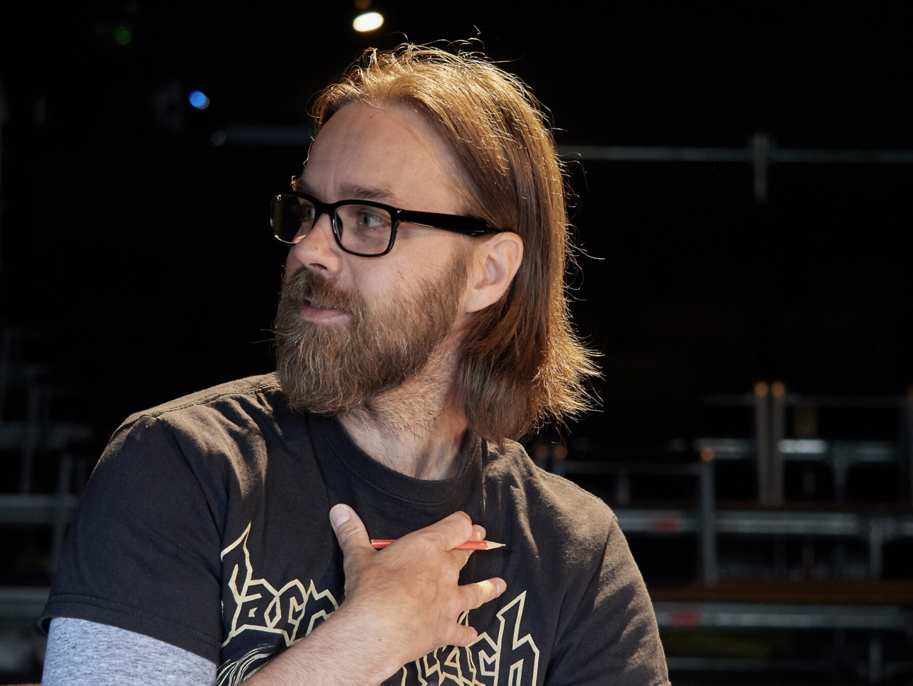 Herr Pešl steht auf einer leeren Theaterbühne, der Blick geht über die Schulter an der Kamera vorbei
