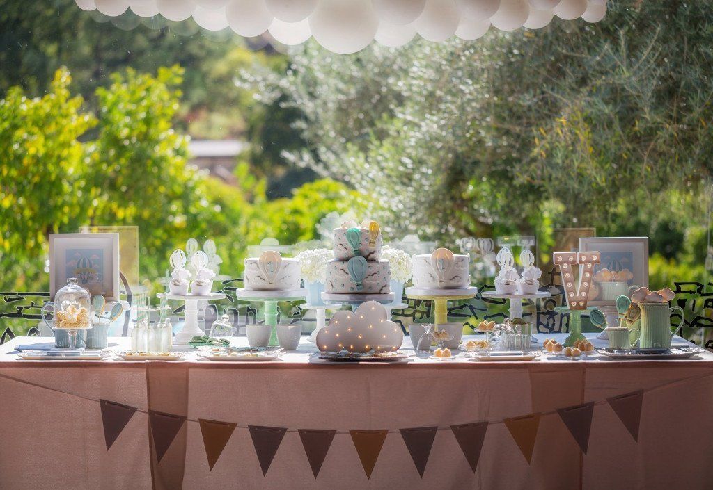 Buffet de baptême joliment décoré, à l'extérieur avec au dessus une guirlande de ballons blancs - event planner