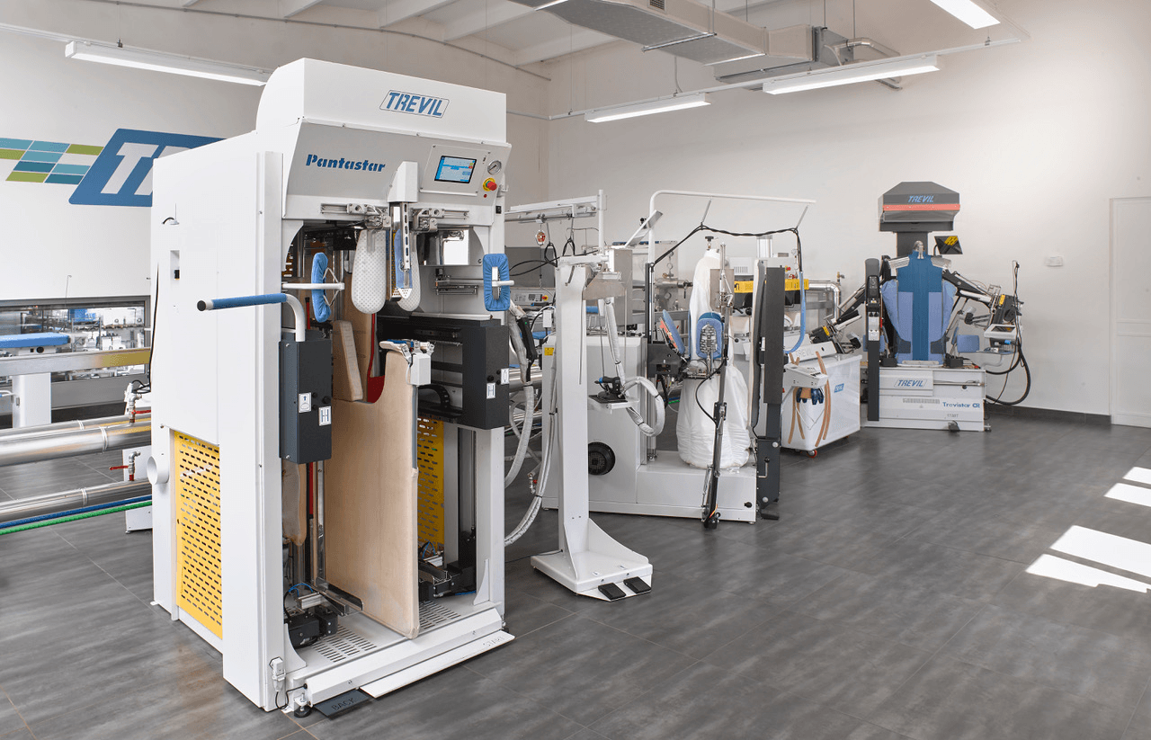 pallas finish systeme gmbh trevil bügelmaschinen ausstellungsraum PALLAS - TREVIL produziert Maschinen für chemische Textilreinigungen, Wäschereien und überall dort, wo ein professioneller Umgang mit Textilien erforderlich ist. Alle unsere Maschinen sind auf Effizienz und Langlebigkeit ausgelegt und erfüllen die höchsten Anforderungen unserer Kunden weltweit. Fortschrittliche Technologie, Forschung und Entwicklung kamen 1995 bei uns zusammen, um der Reinigungsbranche, der industriellen Wäscherei und der Bekleidungsherstellung das Beste an professioneller Ausrüstung zu bieten.