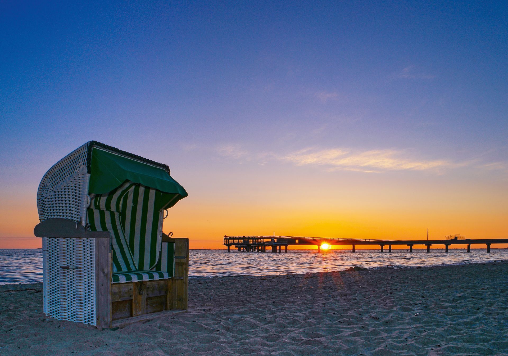 Quelle: Beach Motel Heiligenhafen Sonnenuntergang am Strand neben einem Strandkorb