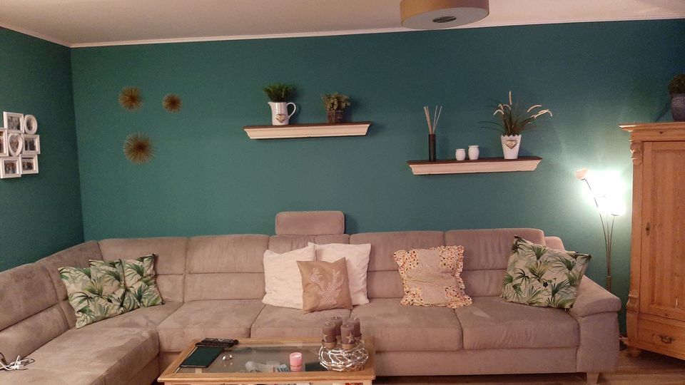 Wohnzimmer mit petrolfarbener Akzentwand hinter dem Sofa
