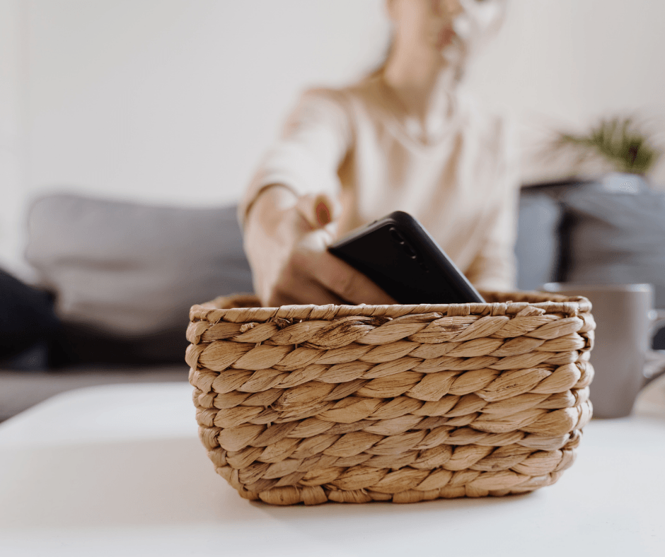 Person placing a phone into a woven basket on a tidy coffee table