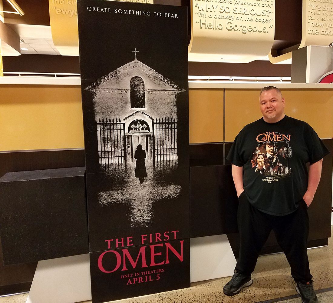 The Omen Online webmaster Paul K. Bisson stands next to The First Omen standee at an AMC Theater