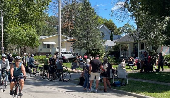 A large crowd listens and bikes coast by at PorchFest DSM 2022