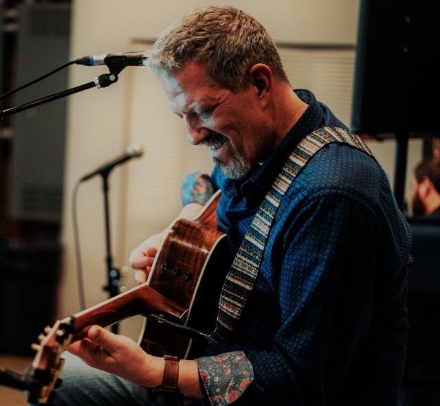 Photo of Corbett Reeves playing guitar and singing