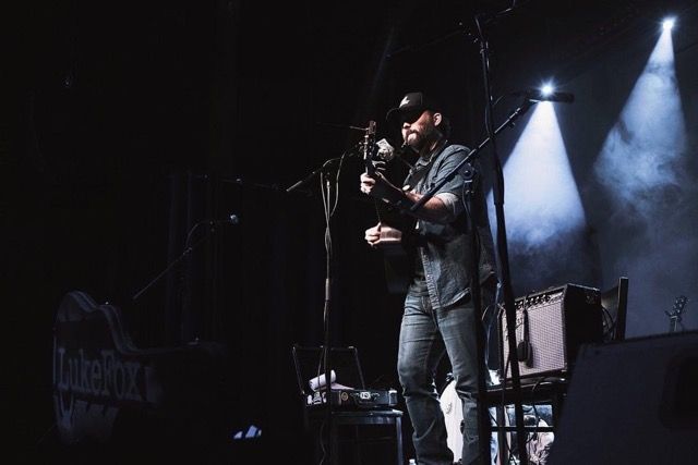 Photo of Luke Fox playing on a dramatically lit stage