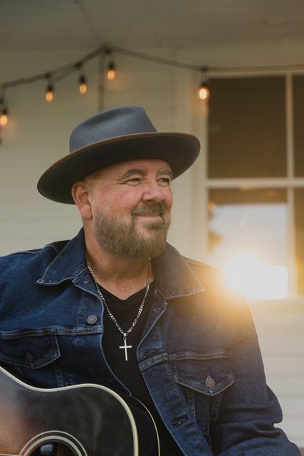 Robert Deitch ready to play his guitar on a welcoming porch