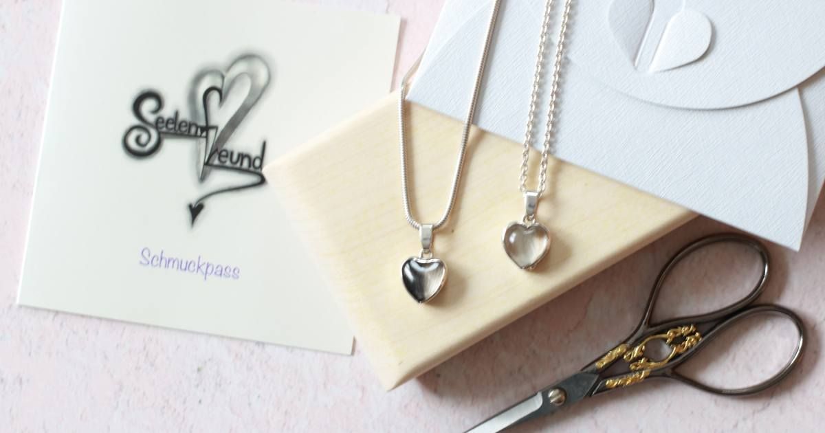 zwei Schmuckstücke von Seelenfreund in Herzform mit eingefassten Tierhaaren.
Neben den Kettenanhängern liegt Arbeitswerkzeug