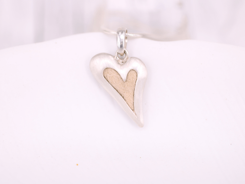 Tierhaarschmuck in Form eines asymmetrischen Herz in dessen Zentrum die Haare ihres Tieres eingearbeitet werden