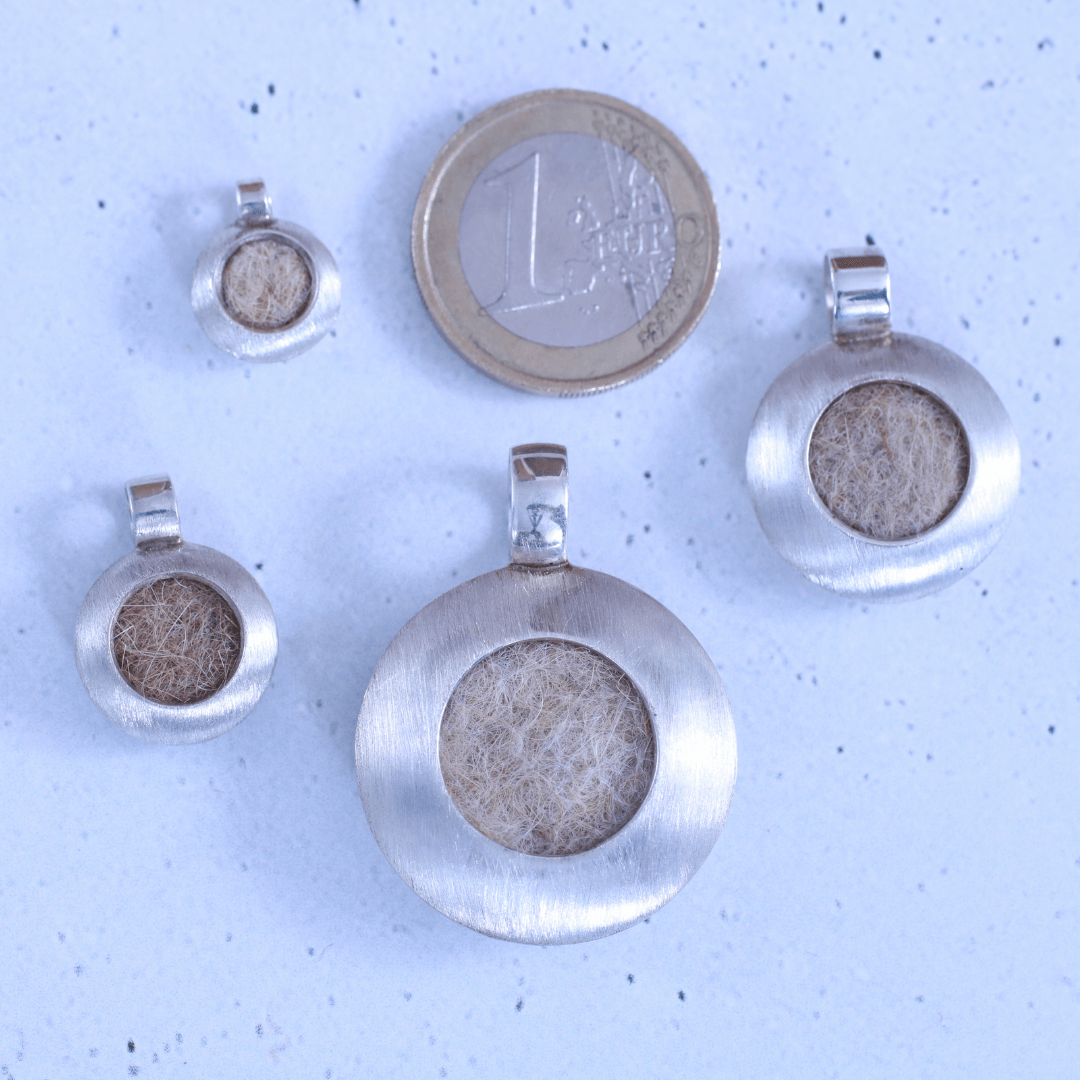 alle vier Größen des Modells Circle vier linsenförmige Kettenanhänger in untersschiedlicher Größe neben einer 1 euro Münze