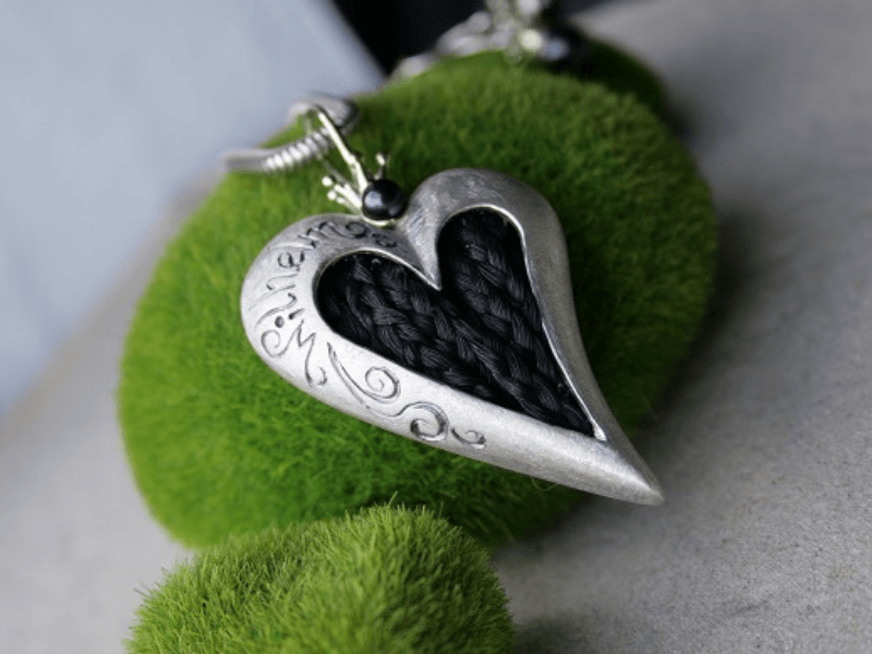 asymmetrischer Kettenanhänger in Herzform mit Zöpfen aus dem Schweif eines Friesen. Der Schmuck ist verziert mit einer Perle