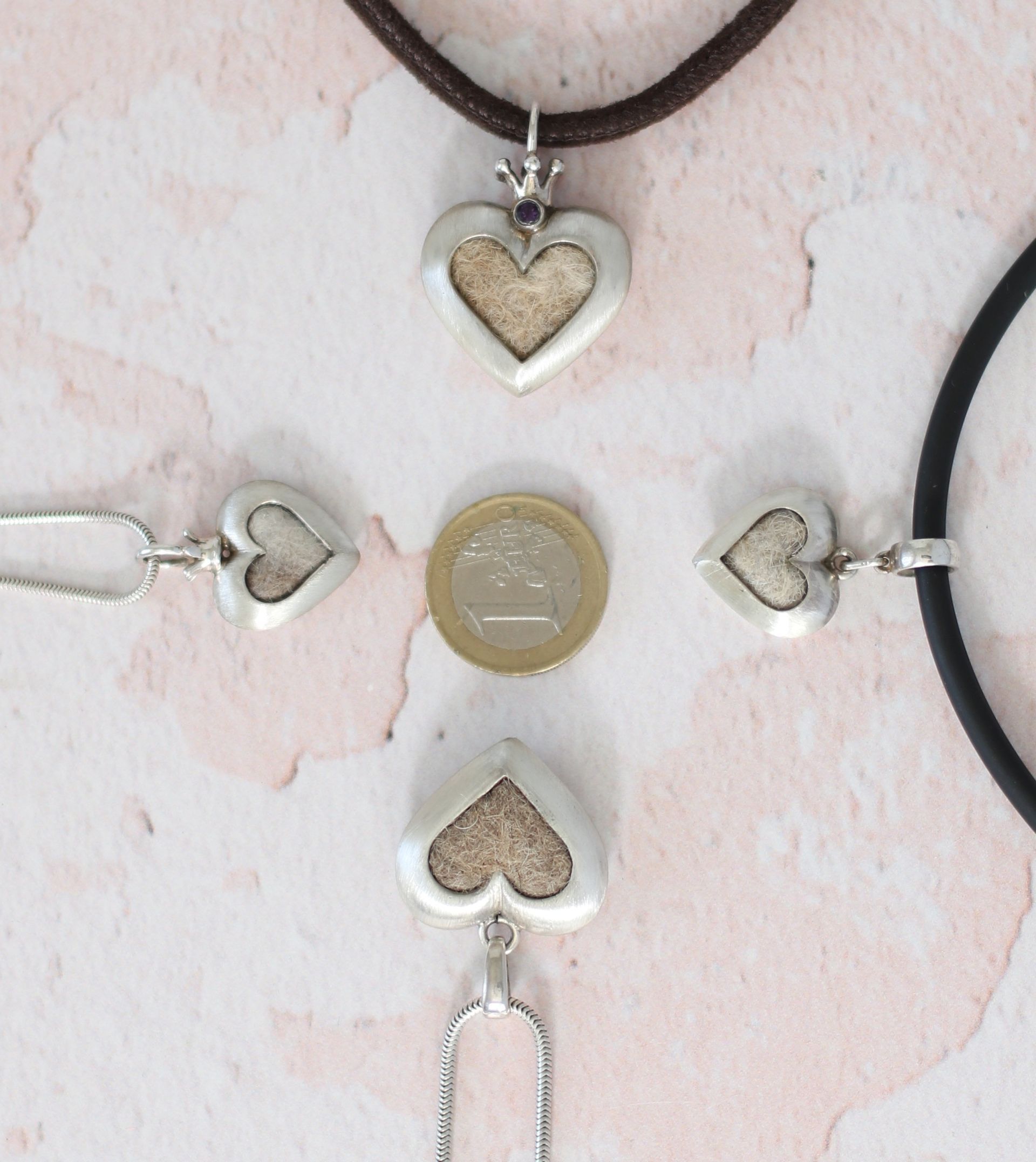 zwei symmetrische Herzanhänger mit Tierhaaren in unterschiedlicher Größe