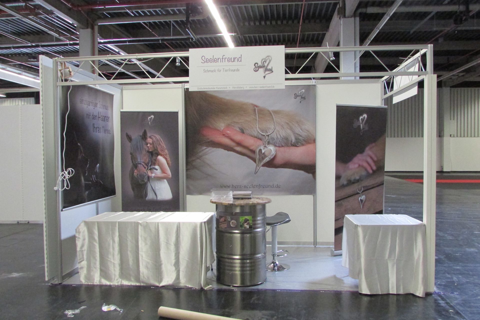 Messestand der Goldschmiede aus Heroldsberg umd auf der Cacib in Nürnberg die Schmuckstücke des Labels Seelenfreund den Besuchern zu zeigen.
Heller Messestand mit emotionalen Bilder auf der Rückwand.