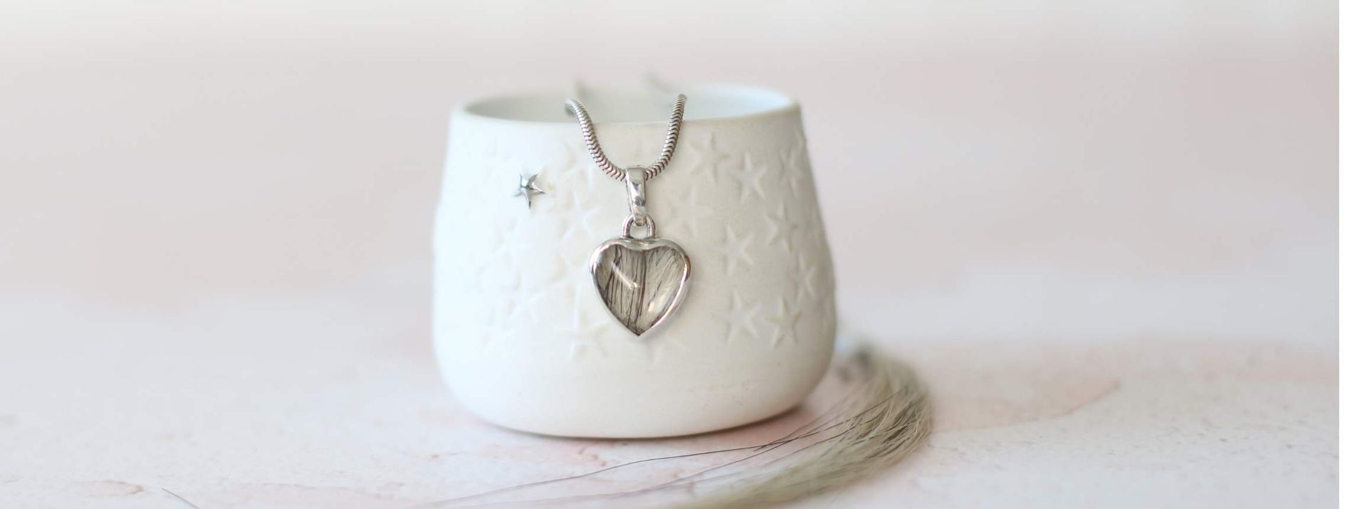 herzförmiger Kettenanhänger mit einer Fassung aus Silber und eingearbeiteten Pferdehaaren.