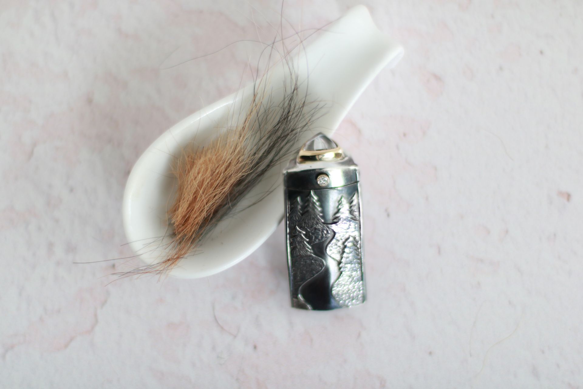 Urnenanhänger Rückseite mit Landschaftsmotiv. Im Deckel sind Haare eingefasst und der Anhänger ist mit Asche gefüllt