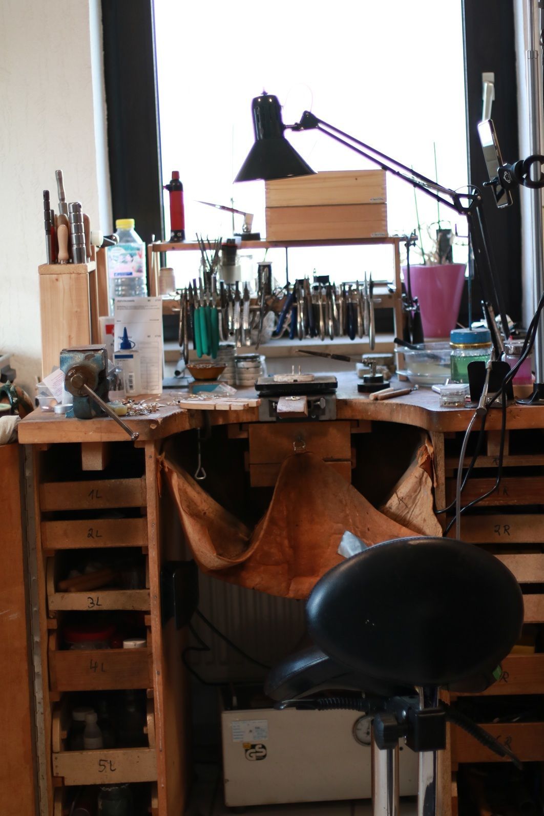 Goldschmiedewerktisch mit Brettfell aus Leder und einem Sattelhocker aus Leder.