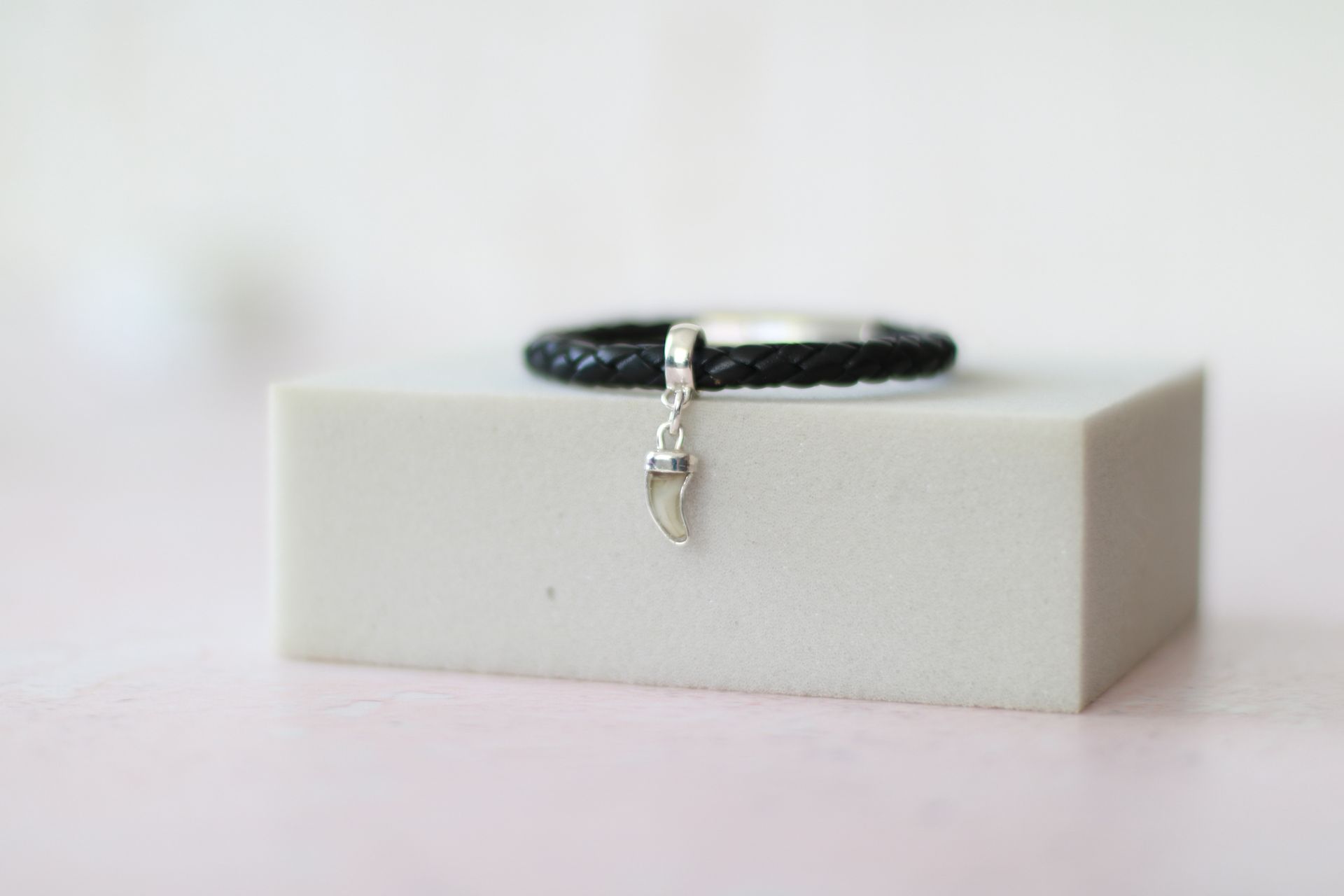 Lederarmband mit einem Beadanhänger mit einem eingefassten Milchzahn, die Fassung ist aus Silber