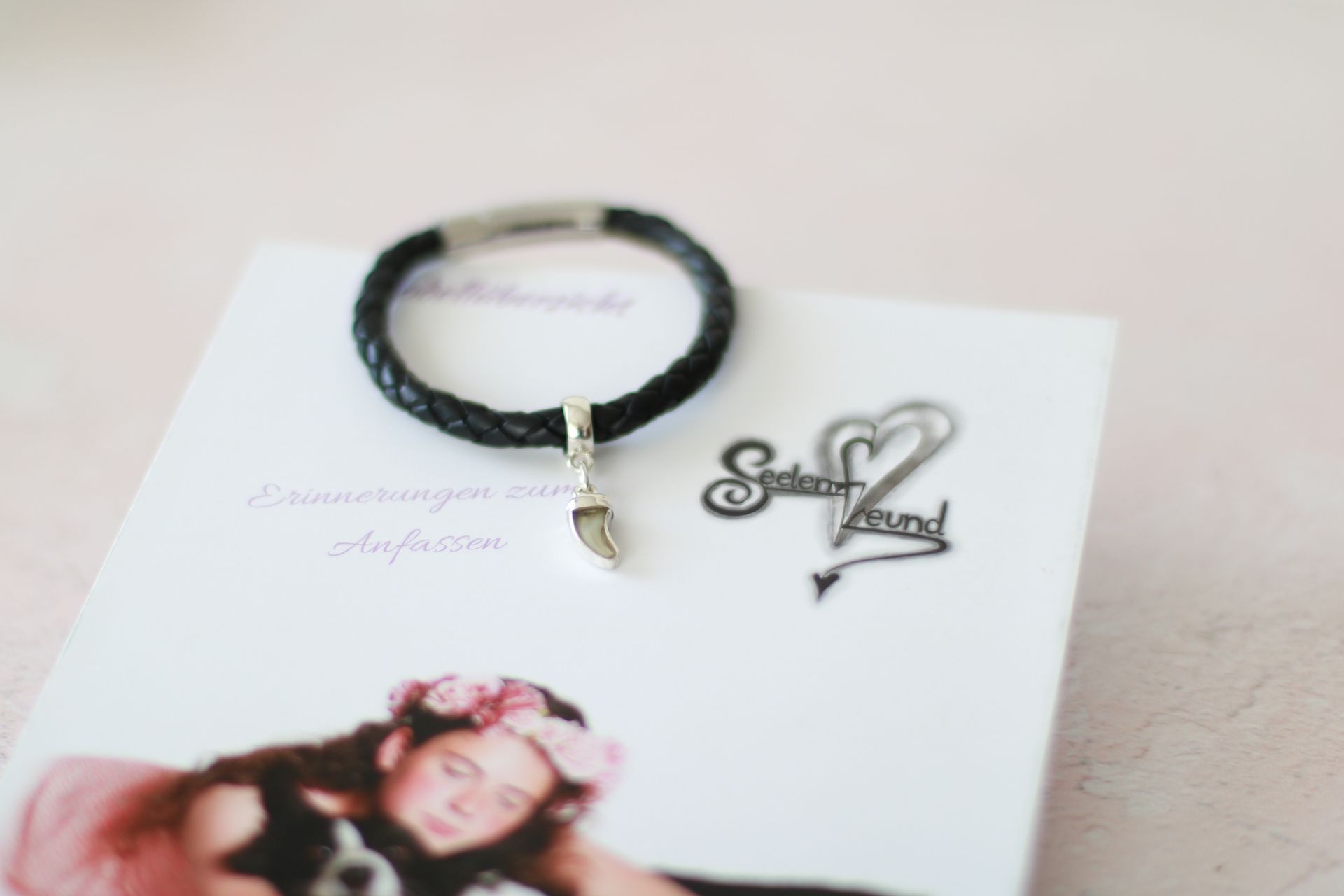 schräger Blick auf einen Flyer von Seelenfreund mit einem Armband mit einem Anhänger mit eingefasstem Zahn