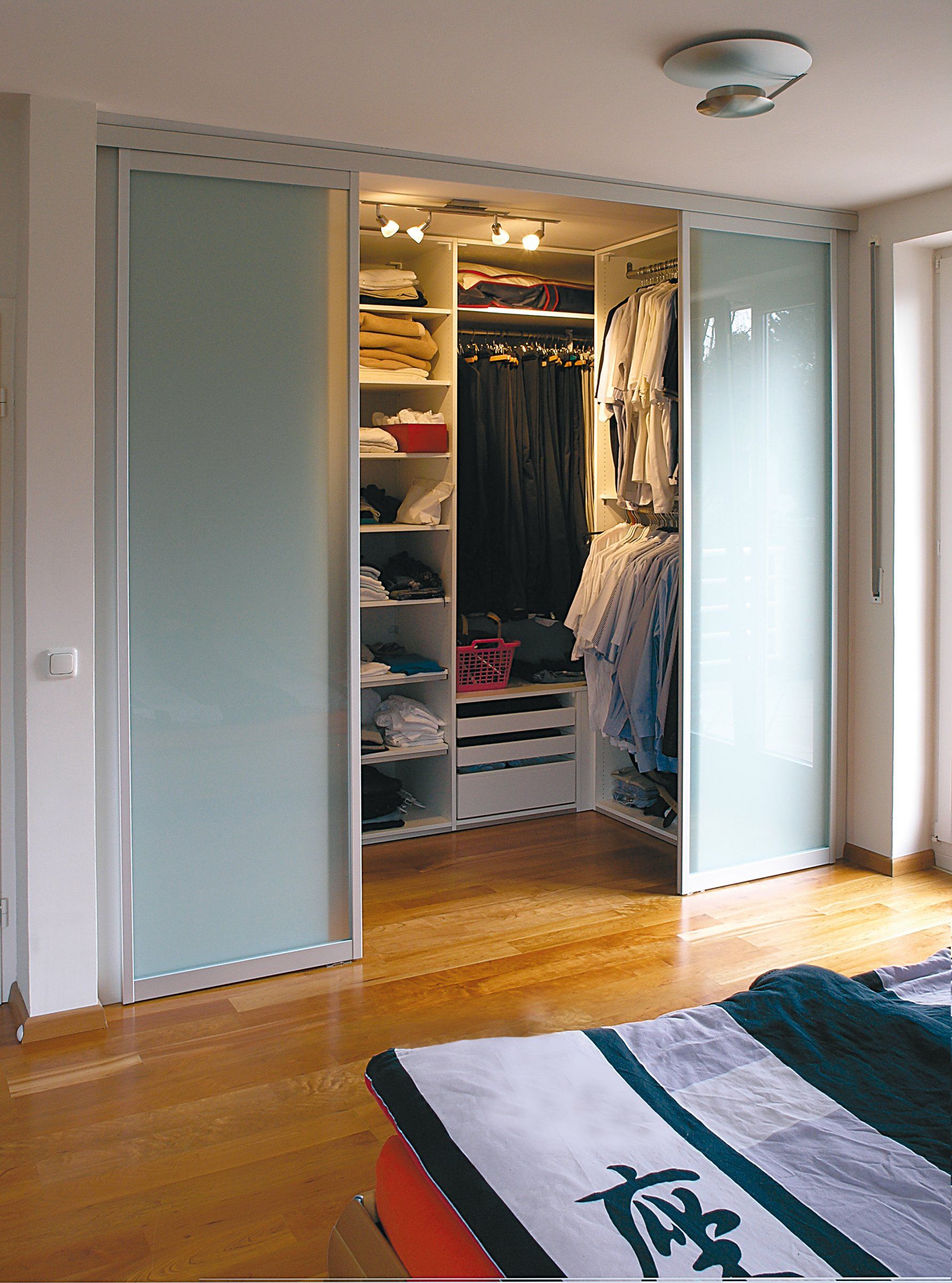 Kleiderschränke mit Schiebetüren von ip20 Möbel nach Maß – hier mit geöffneten Glastüren.