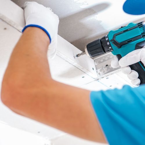 Trockenbauer der grade eine Rigips wand anschraubt