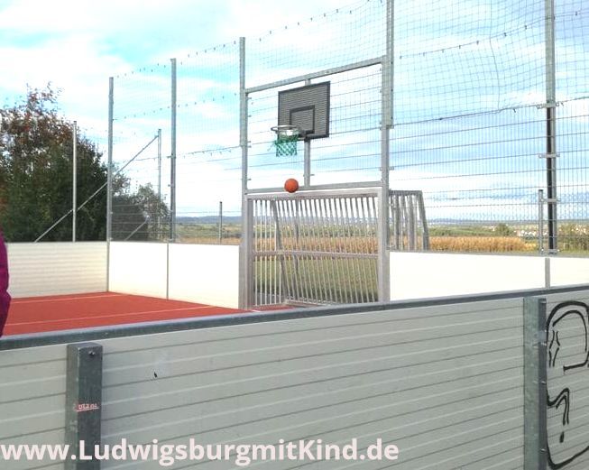 Ein Kind sitzt auf der Bande beim Basketballplatz, der so genannte