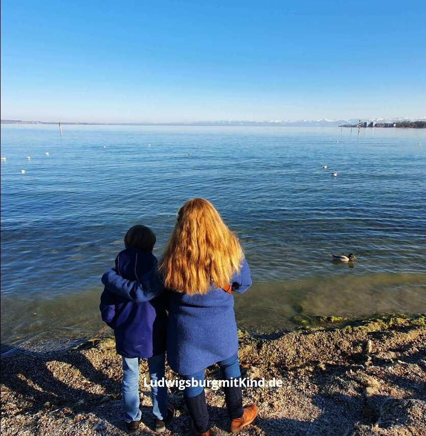 Eine Mutter und ein Kind stehen am Bostalsee und schauen auf den See hinaus.