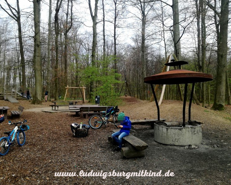 Ein Junge schnitzt an einer Feuerstelle auf dem Waldspielplatz in Ludwigsburg
