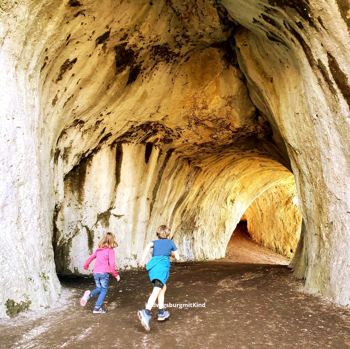 Zwei Kinder laufen durch eine Höhle bei einer Familienwanderungen auf der Schwäbischen Alb.