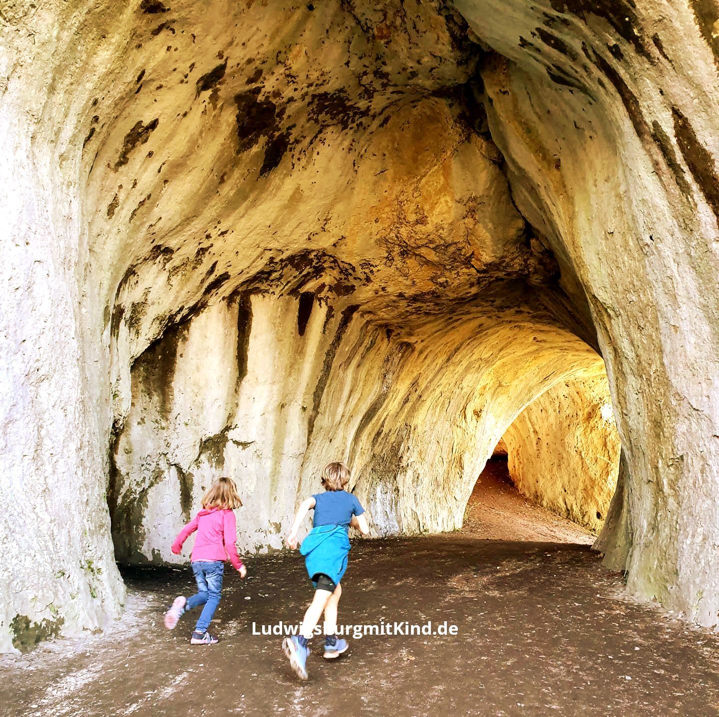 Kinder laufen in einer Höhle bei einer Familienwanderung in Heubach auf dem Rosenstein Bergmassiv auf der Ostalb