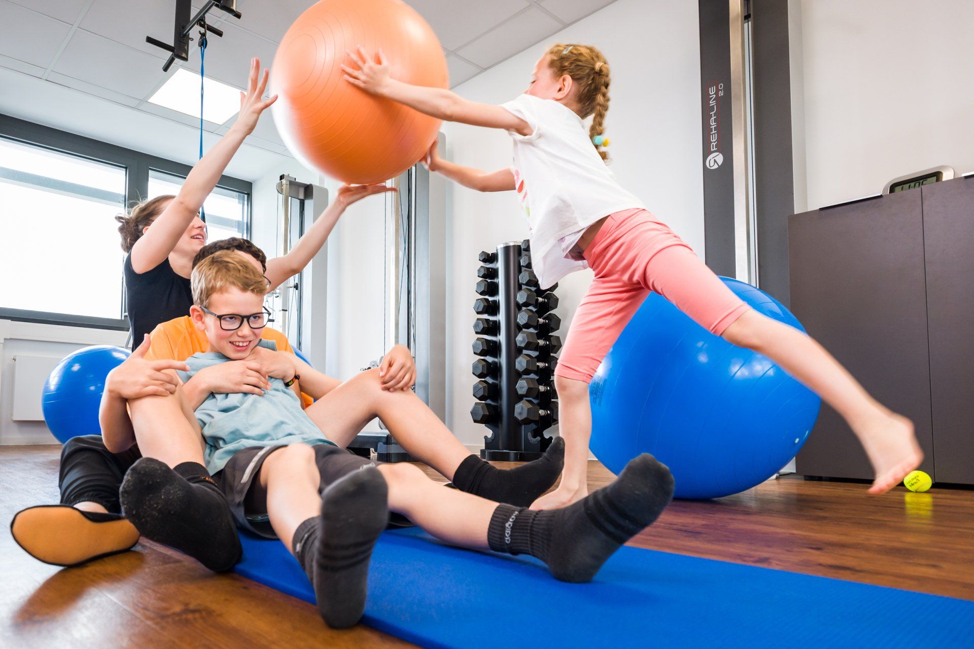 Kinder spielen beim Physiotherapeuten mit einem Ball