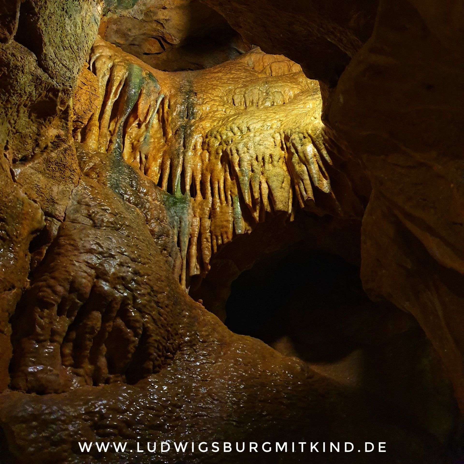 Zwei Kinder laufen durch eine Höhle bei einer Familienwanderungen auf der Schwäbischen Alb.