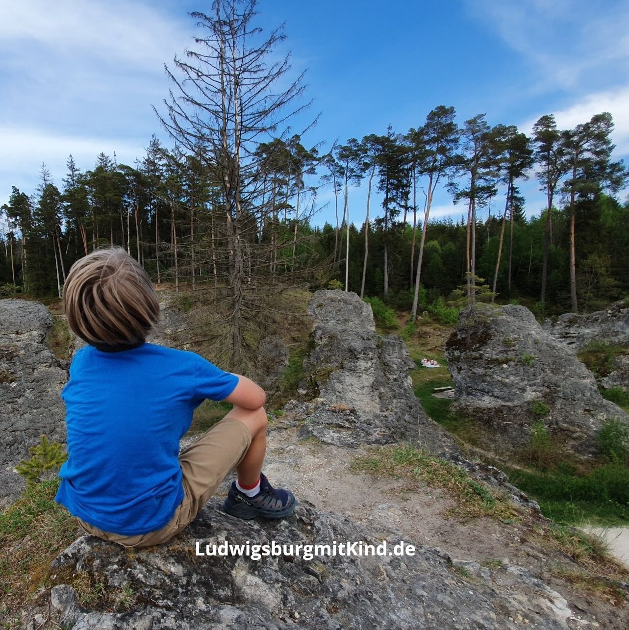 Kind sitzt auf einem Felsen im Wental Felsenmeer auf der Schwäbischen Alb.
