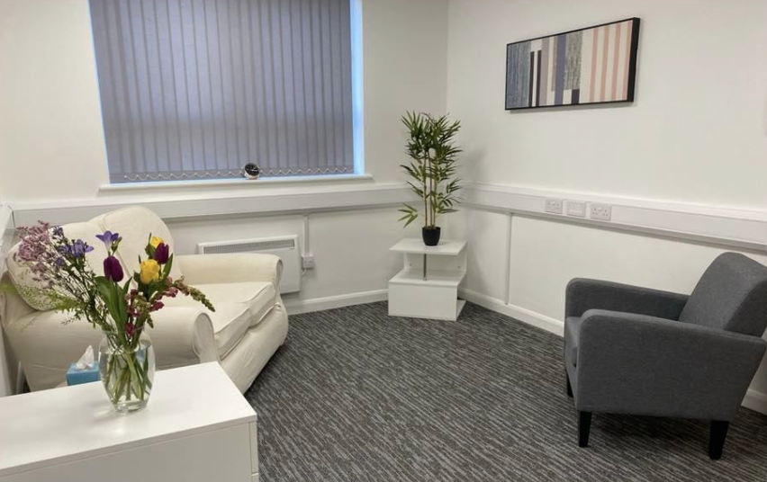 A calm room with sofas and flowers where young people are treated for mental health illness at Wellbeing Therapy Solutions