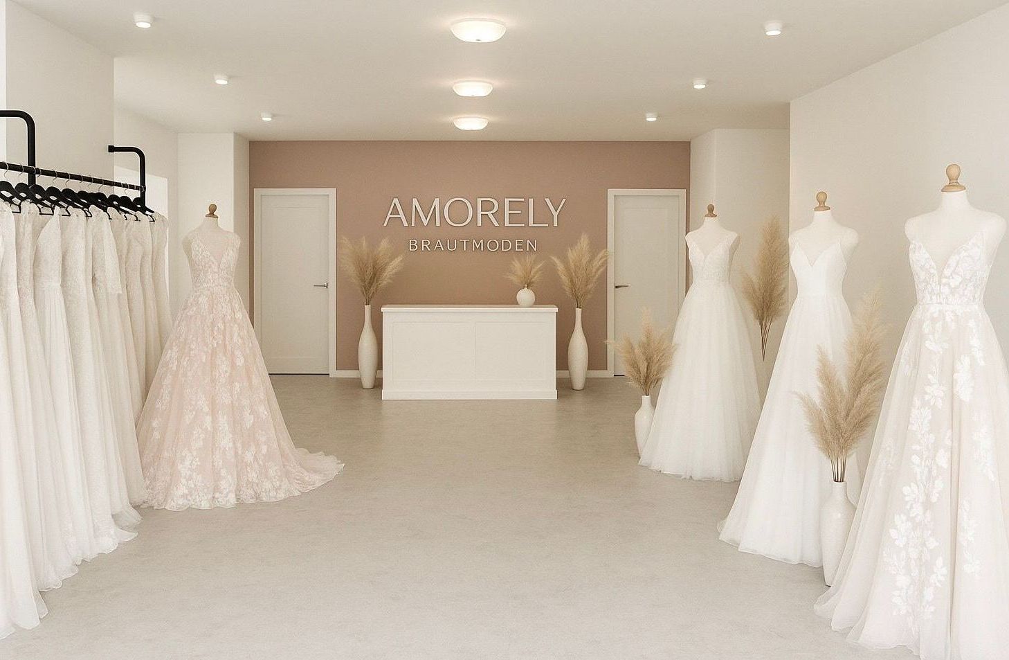 Das Bild zeigt den großzügigen, stilvoll eingerichteten Eingangsbereich von AMORELY Brautmoden Velbert, in der Nähe von Remscheid. Im Hintergrund steht eine weiße Theke vor einer rosafarbenen Wand mit dem Marken-Schriftzug „AMORELY BRAUTMODEN“. Links im Bild hängen Brautkleider in verschiedenen Stilen, Farben und Silhouetten ordentlich auf einem schwarzen Kleiderständer. Daneben steht eine Schneiderpuppe mit einem A-Linien-Brautkleid, das mit aufwendiger Blütenspitze verziert ist. Rechts im Bild stehen weitere dekorative Brautpuppen mit schlichten, eleganten Kleidern. Große weiße Vasen mit Pampasgras setzen warme Akzente. Der Raum wirkt freundlich, einladend und modern – ein stilvolles Ambiente, das sofort Vertrauen und Vorfreude auf die Anprobe vermittelt.