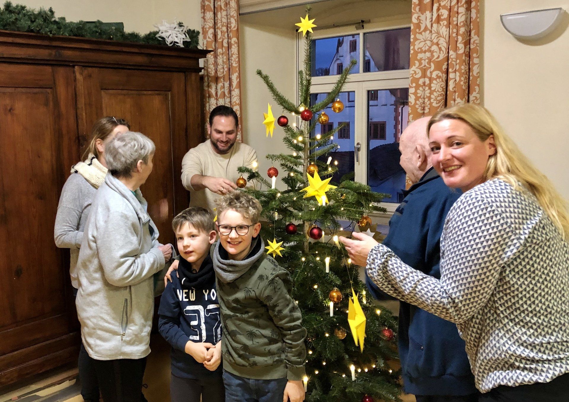 Anja Heinisch, Nina Sahlmüller, Matthias Bielek mit den Senioren im Hornschen Spital beim Schmücken des Weihnachtsbaumes