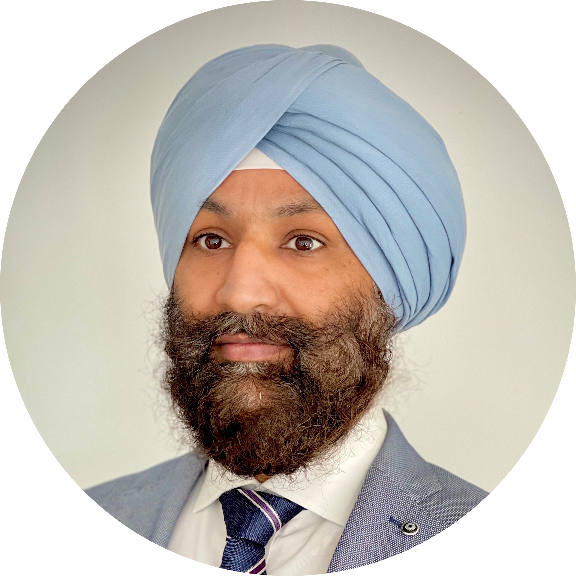 Headshot of Amrit wearing a pale blue suit, dark blue and white tie, and pale blue turban, against a grey background.