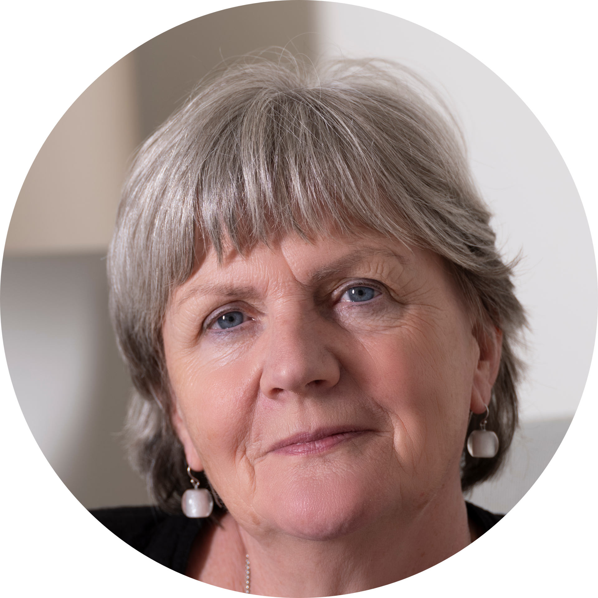 Headshot of Gill with grey cropped hair and silver earrings.