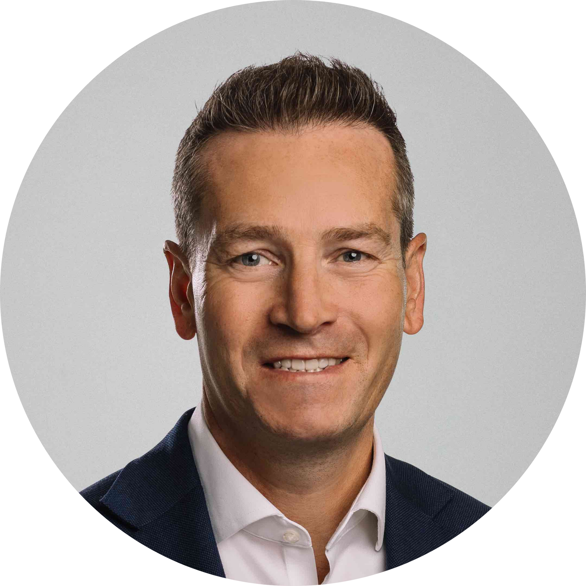 Headshot of Simon smiling against a grey background