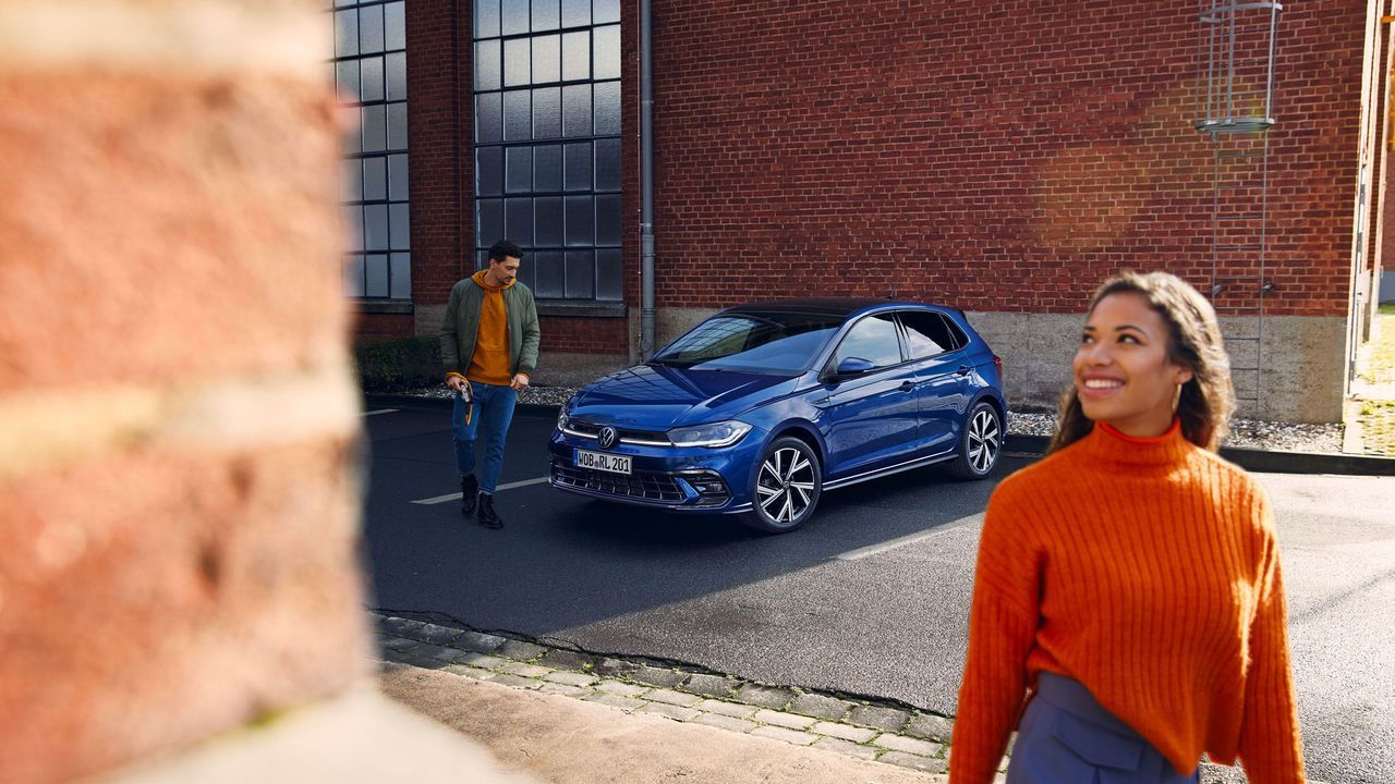 Frau steht vor einem blauen VW Polo