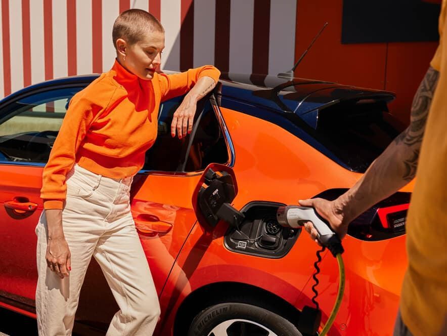 Frau beim laden eines Elektro Corsa