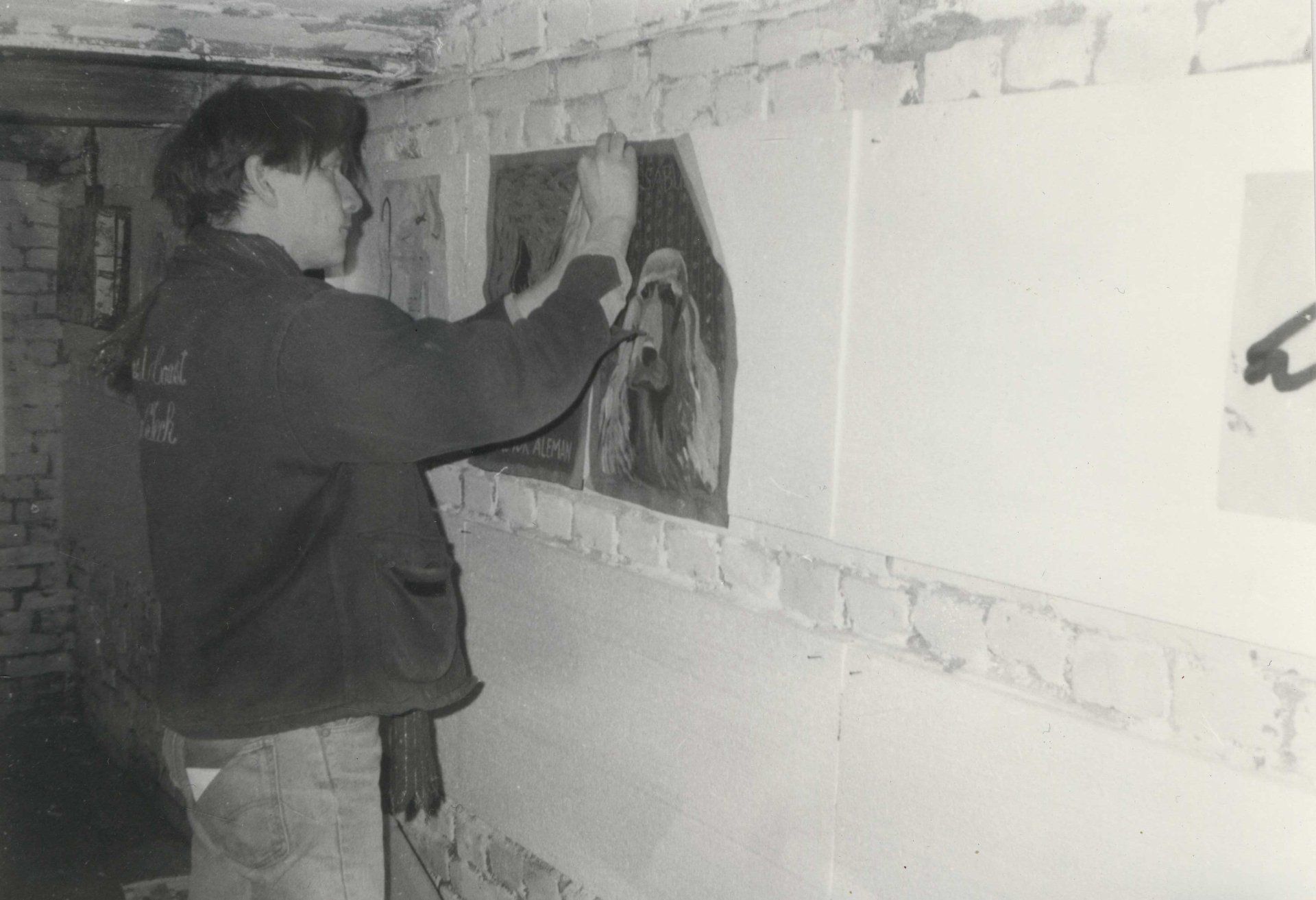 David Boysen/co-founder of Fischbüro, hanging BOX exhibition, dog painting by Fernando Bryce, Fischbüro cellar, 1987 Fischbüro