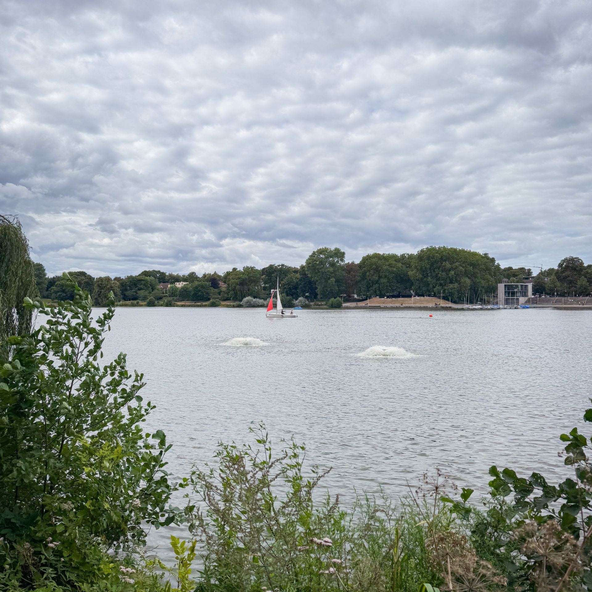 Blick auf den Aasee, auf dem ein Segelboot fährt