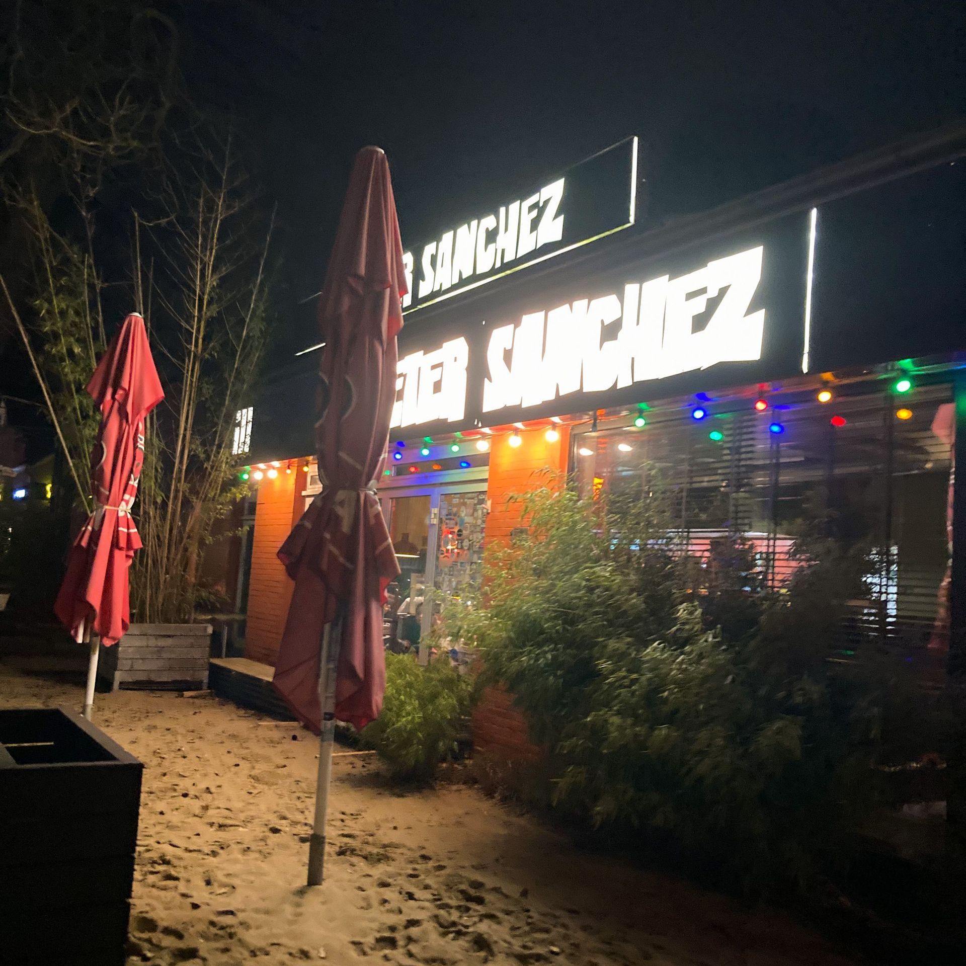 Hamburg entdecken Restaurant Dieter Sanchez zwei zugeklappte Sonnenschirme im Hintergrund das bunt beleuchtete Restaurant
