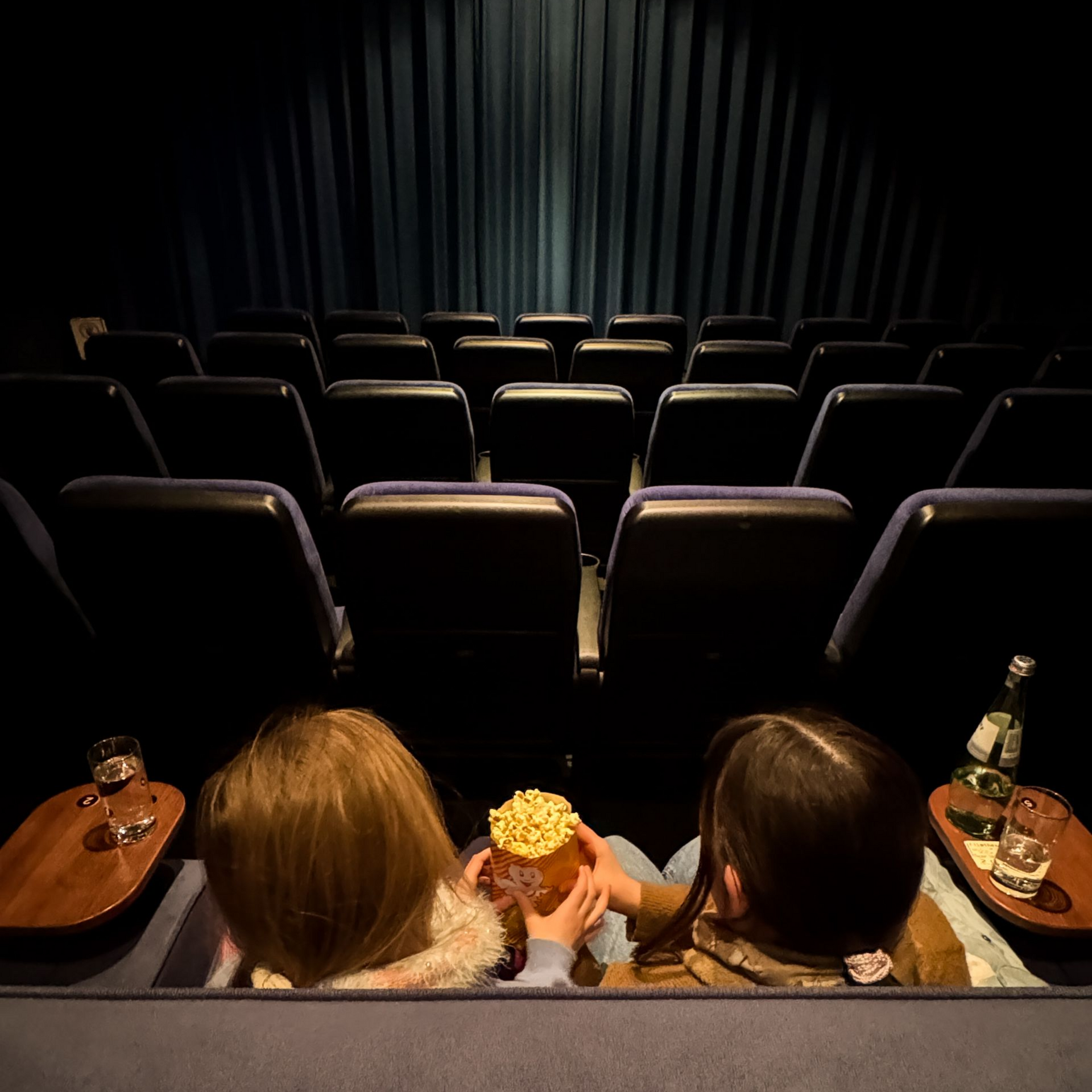 Schleswig-Holstein Tipp Blick auf zwei Kinder die auf einem Sofa im Kino sich Popcorn teilen