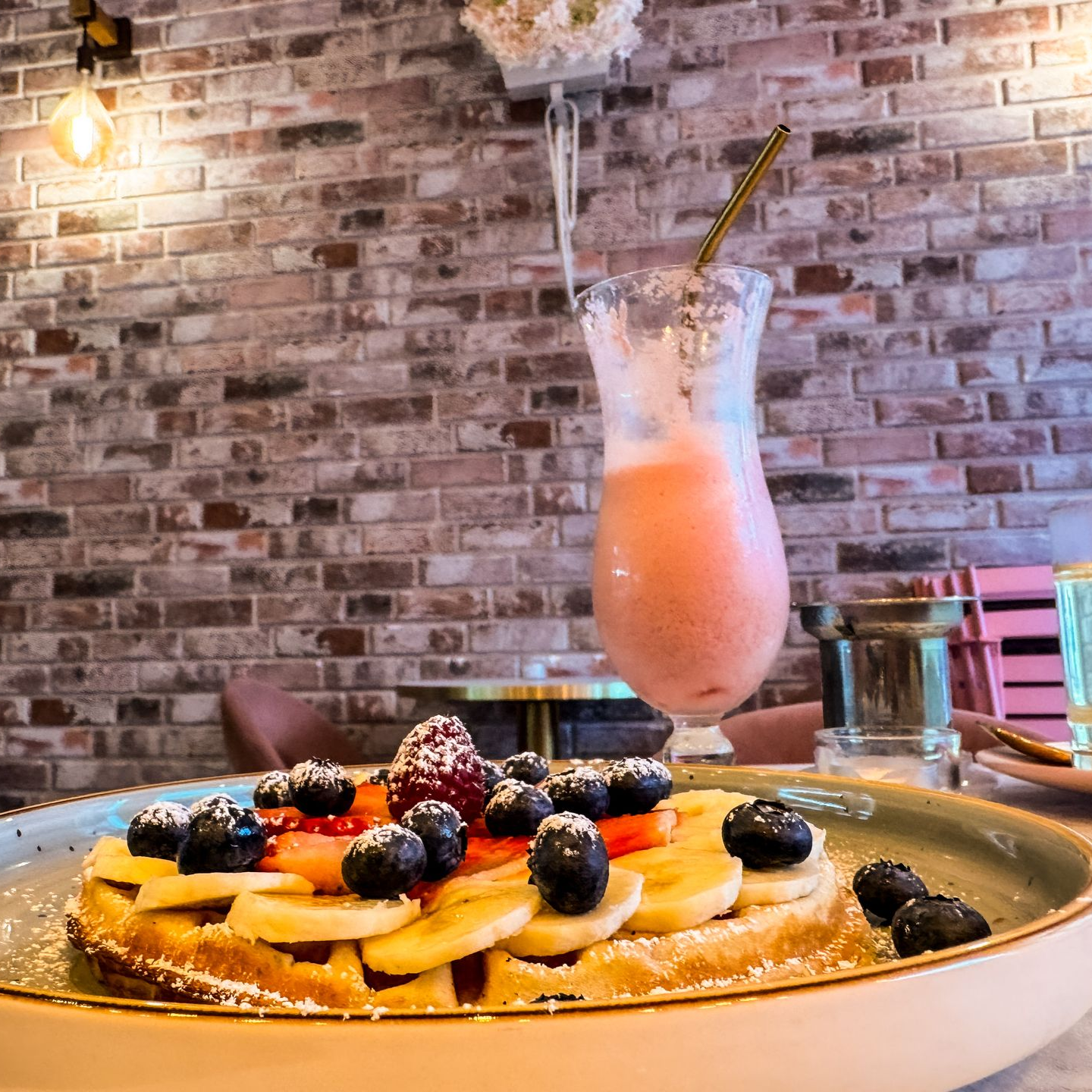 Blick auf einer mit Obst belegten Waffel und einem Fruchtshake im Lecker Wecker Cafe
