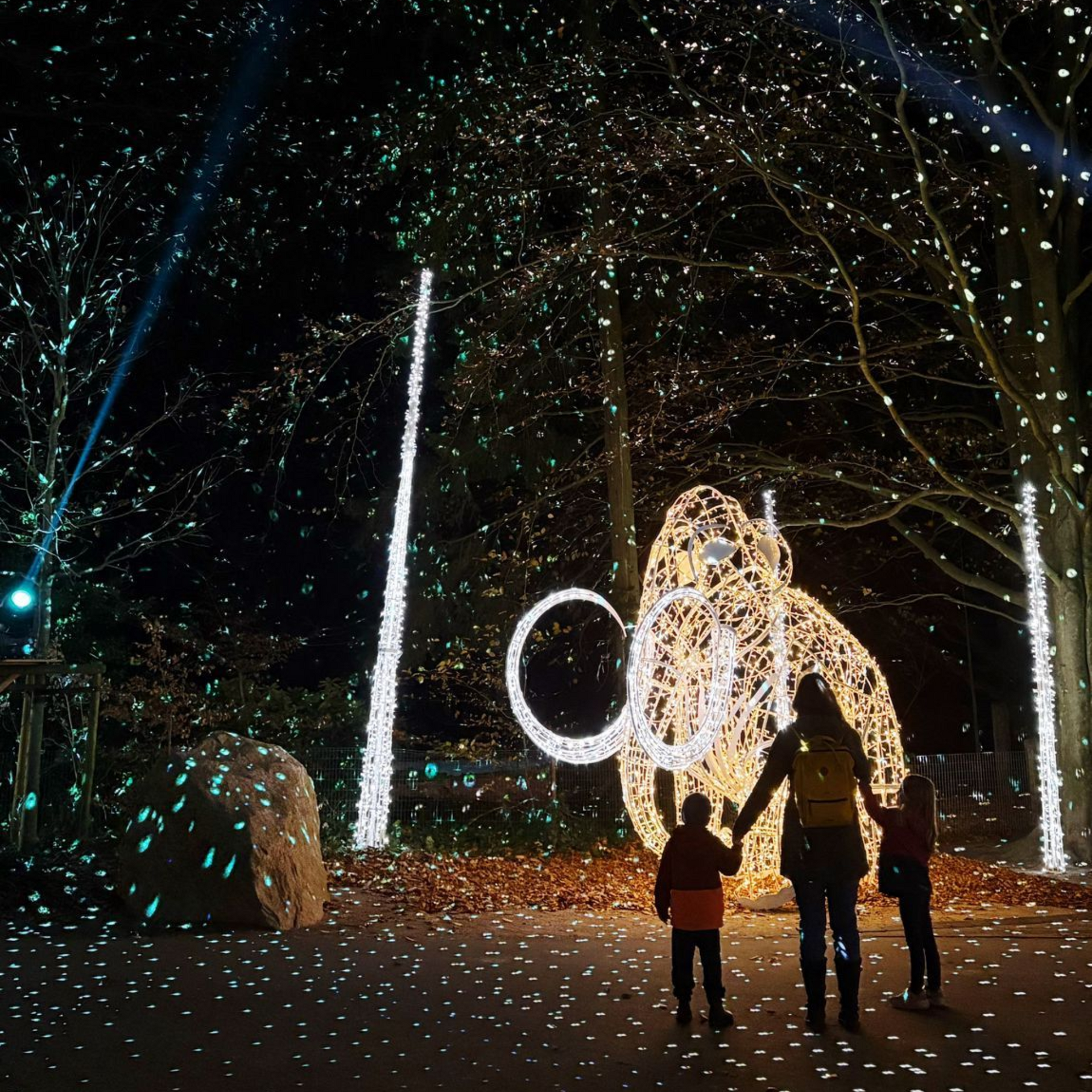 Blick auf eine Frau mit zwei Kindern, die vor einen leuchtenden illuminierten Elefant stehen