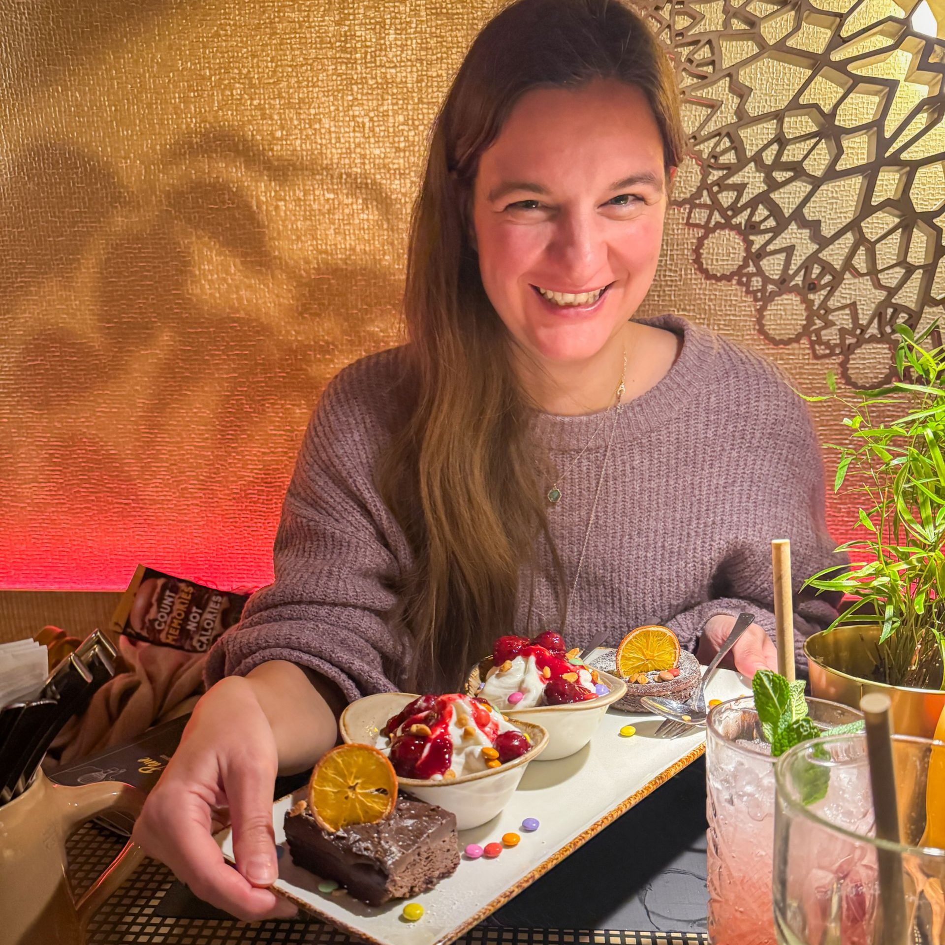 Frau sitzt lachend hinter einer Dessert Platte