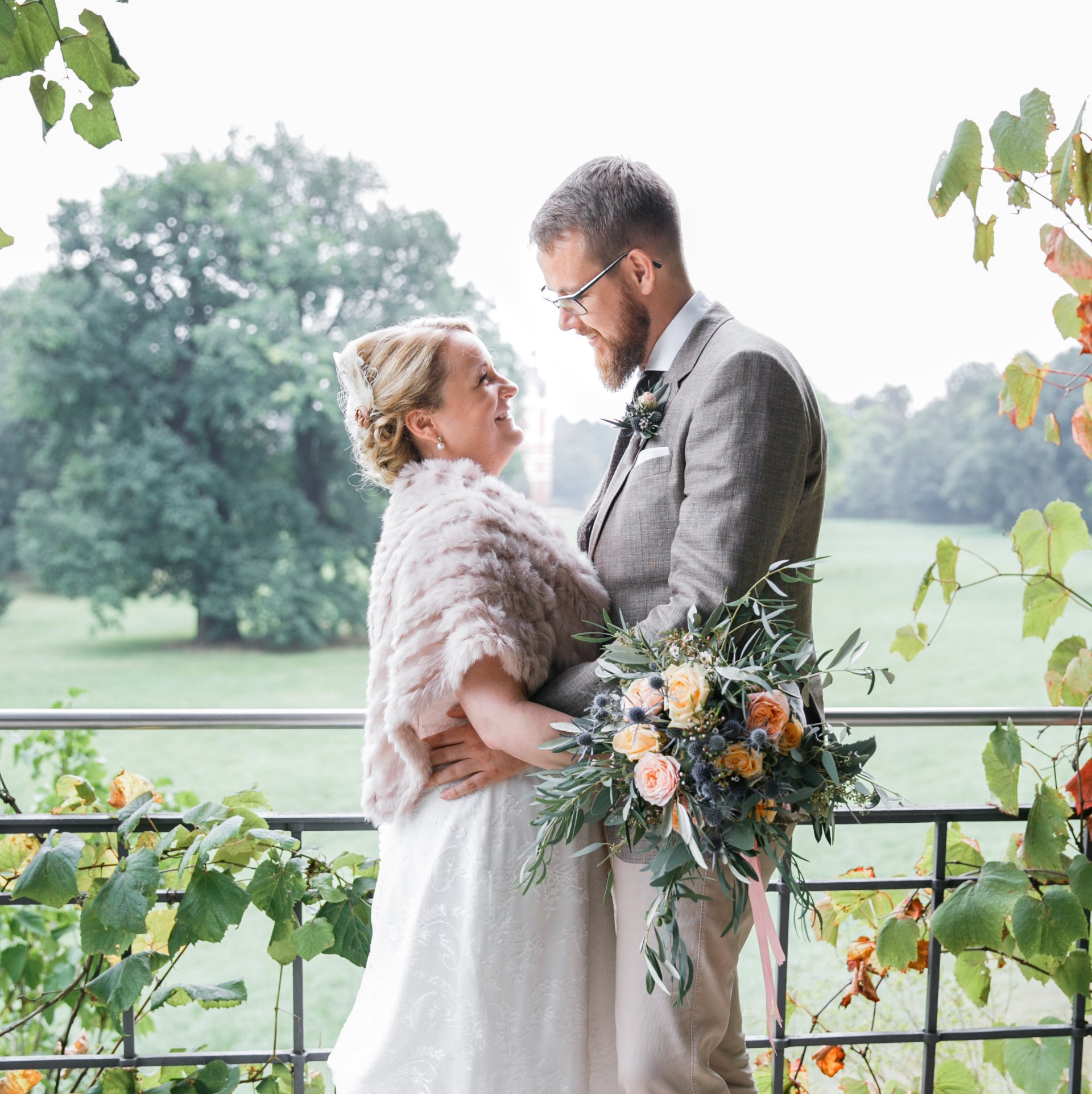 Katja & Christoph, glücklich verheiratet Hochzeitspaar schaut sich liebend in die Augen, bunter Blumenstrauß sichtbar im Vordergrund