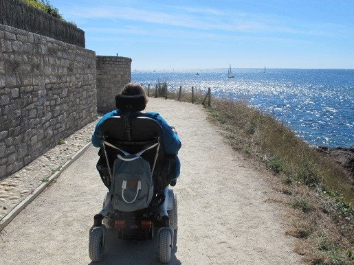 Assistenz im Urlaub Frau im Rollstuhl am Meer