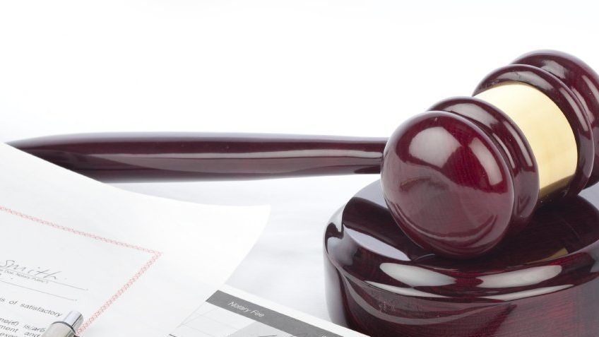 A wooden judge's gavel lies next to legal documents on a white background on inheritance tax in Italy